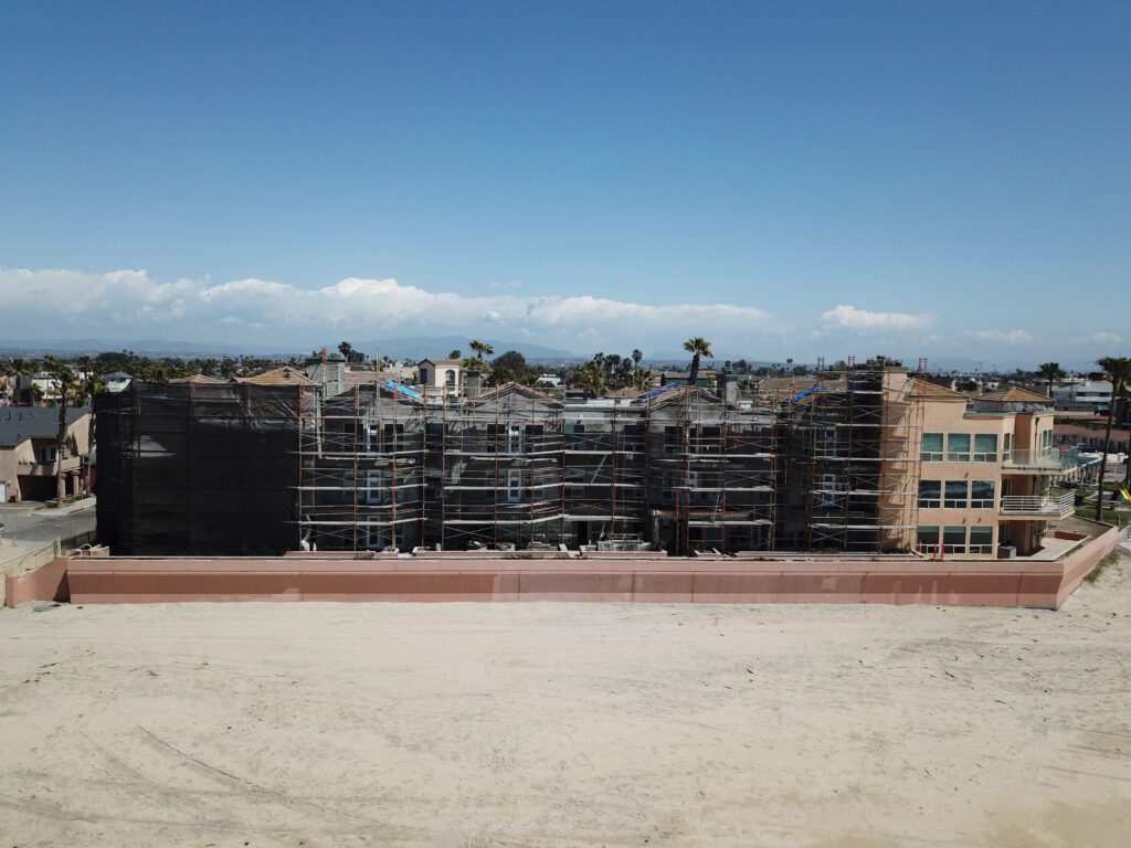 Construction site with scaffolding on a large building under a clear sky.